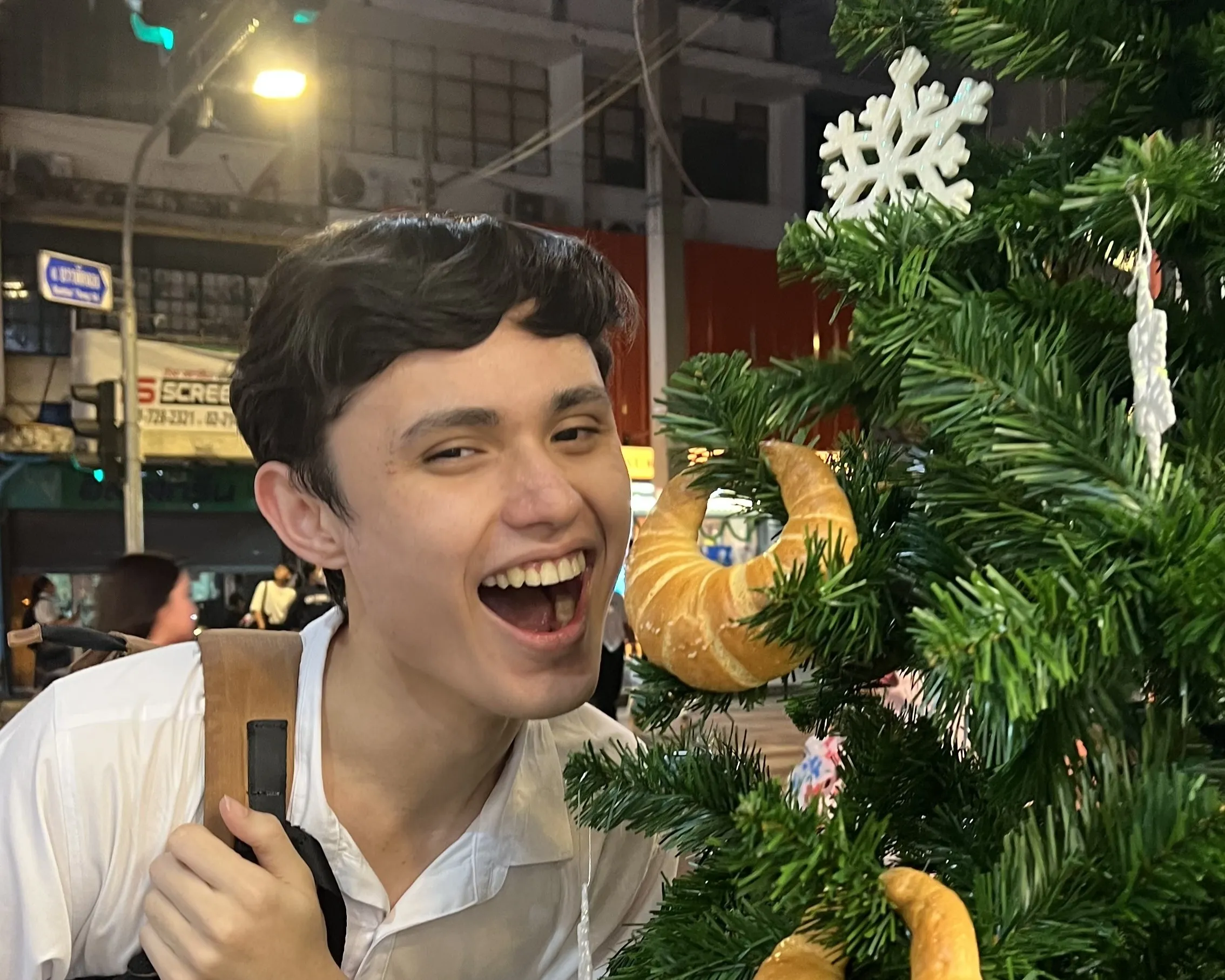 Ryan posing with a croissant-decorated christmas tree
