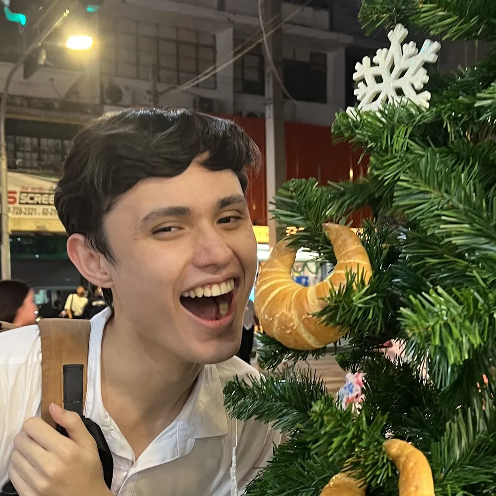 Ryan posing with a croissant-decorated christmas tree